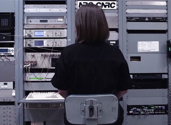 Woman with black hair sitting in front of computational equipment