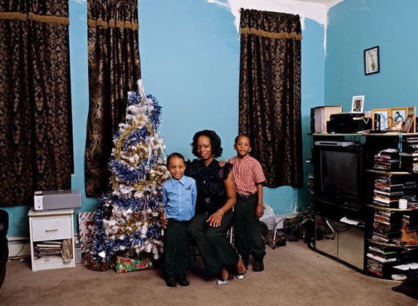 A woman and two children pose next to a Christmas tree richly adorned.